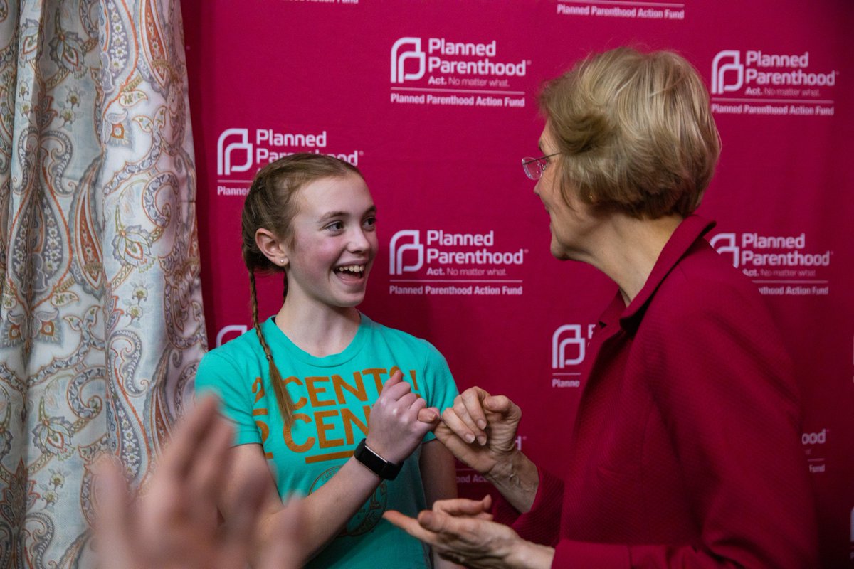 A girl makes a pinkie promise with Elizabeth Warren.