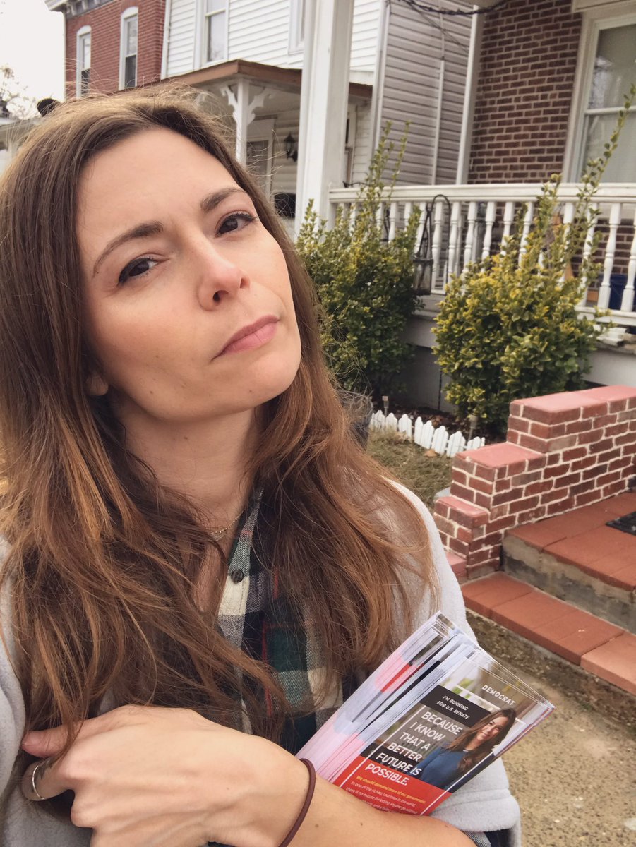 Jess Scarane holding campaign literature and canvassing a neighborhood in Wilmington, Delaware