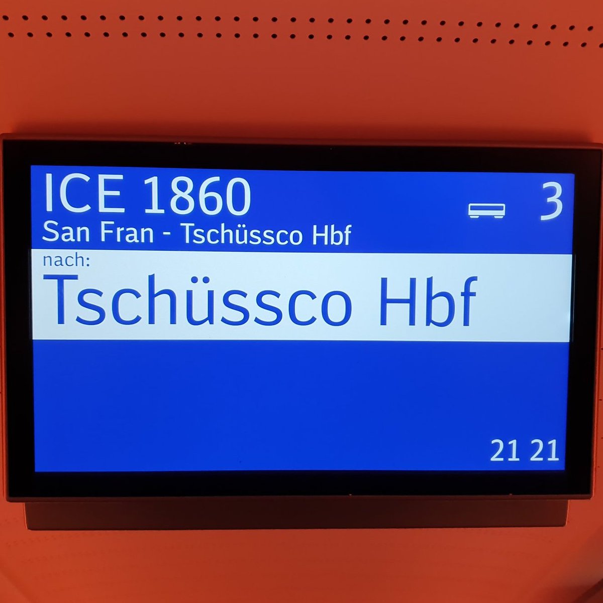 Zu sehen ist der Deckenbildschirm in einem ICE, darauf ICE 1860 nach "San Fran Tschüssko"-Hauptbahnhof.
