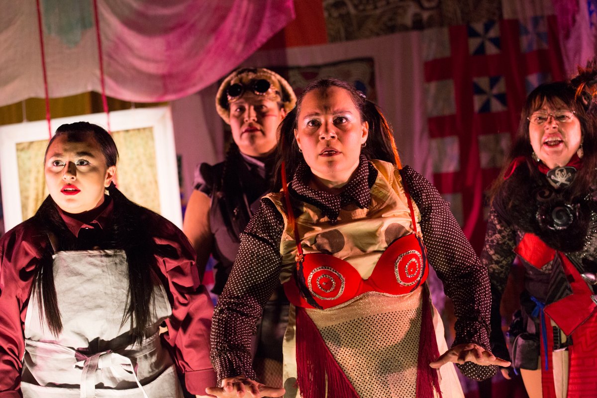 Four actors dressed in red clothing looking into the distance. 