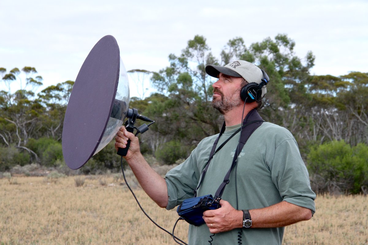 photo of a bearded white man holding sound recording equipment outdoors