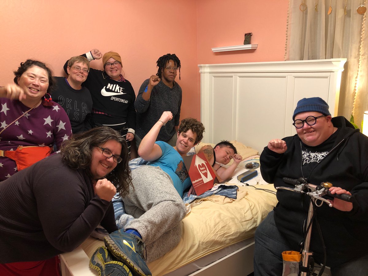 Group selfie of disabled people in Stacey’s bedroom w fist raised