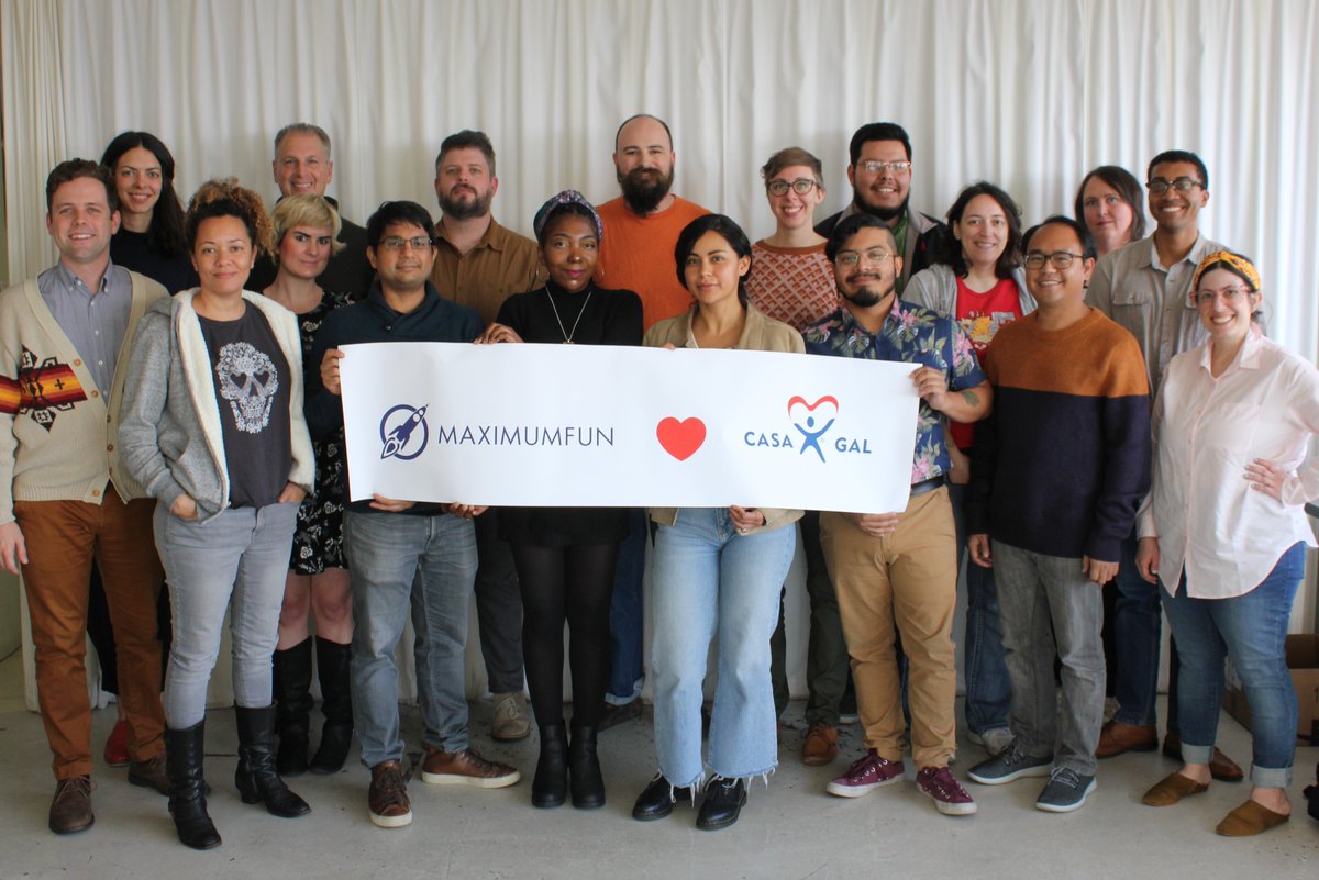 Maximum Fun staff holding a banner that says "Maximum Fun [heart] CASA/GAL