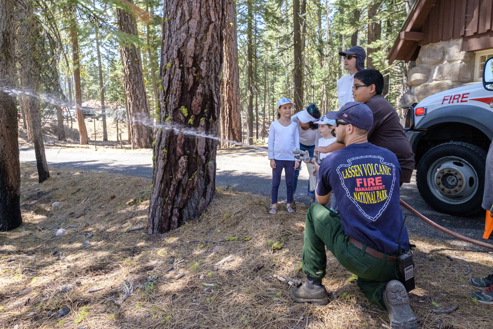 Fireman sprays water hose with kids