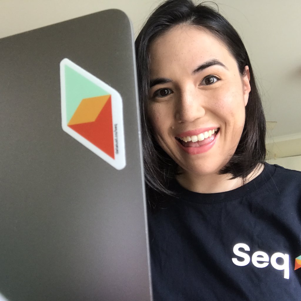 Larene wearing a Seq T-shirt in front of a laptop with a Seq sticker on it