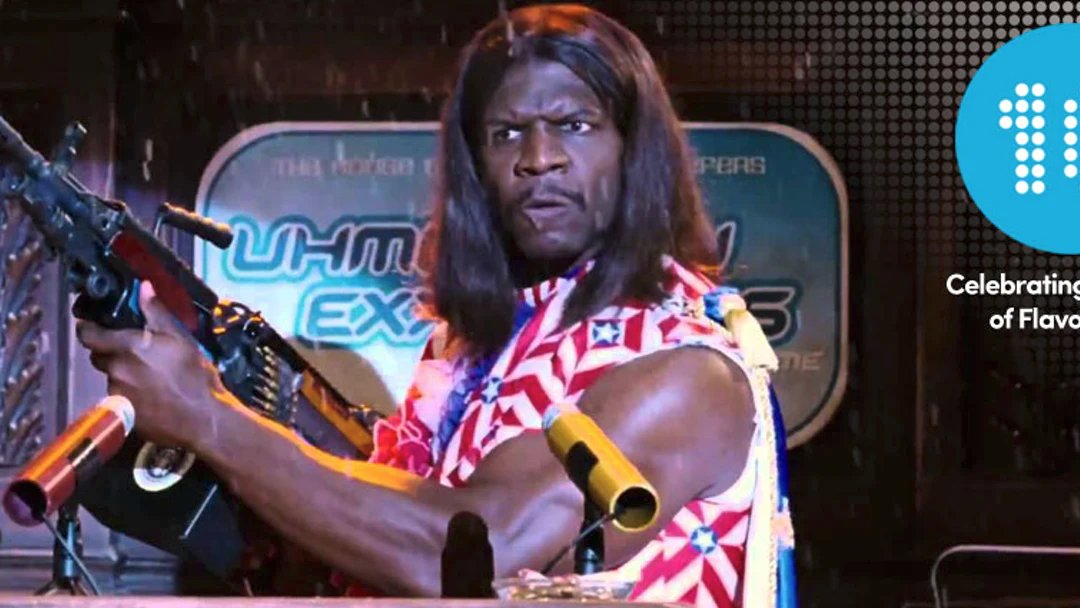 Camacho in Idiocracy with a big gun while waering an American flag shirt and cape