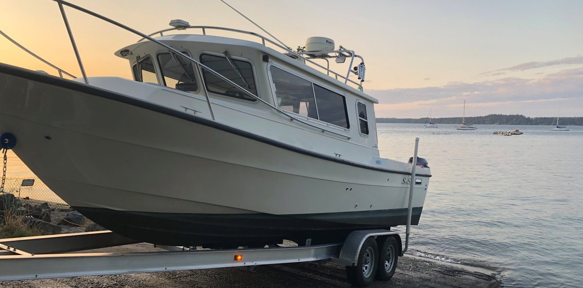 Boat on trailer being backed down boat ramp into Puget Sound.