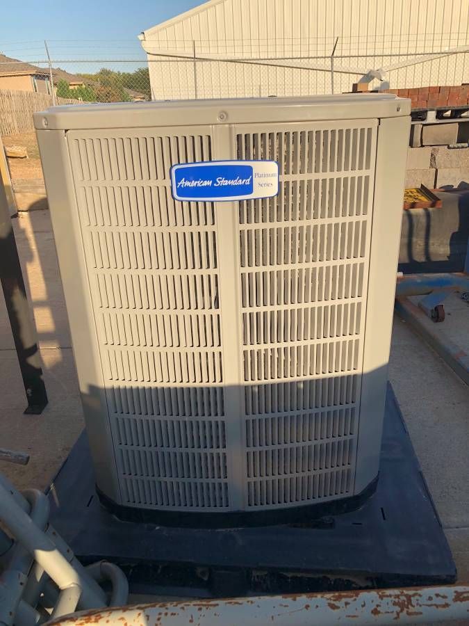 A misaligned photo of an American Standard Platinum Series AC unit in a concrete area.
