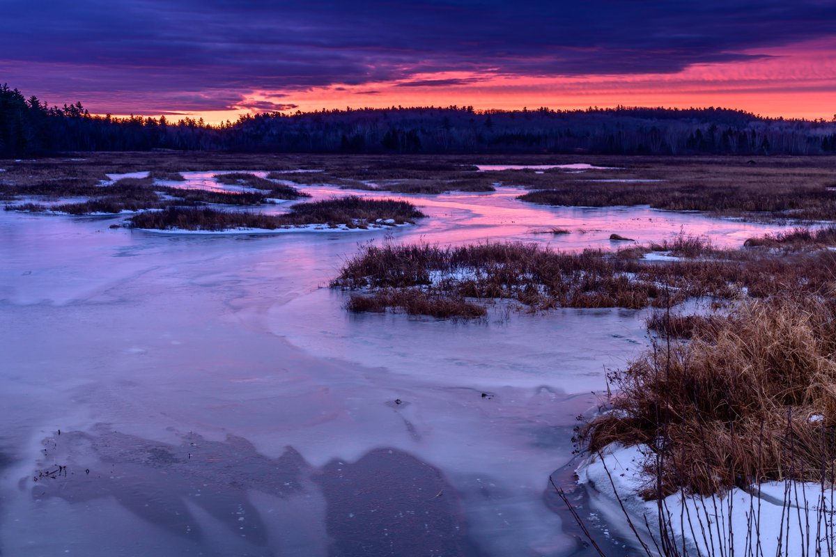 Swirling ice under a bright orange and pink sunrise in Maine