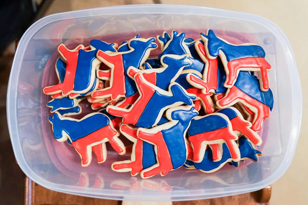 A Tupperware container of donkey cookies, frosted with blue frosting on the top half, and red frosting on the bottom half.