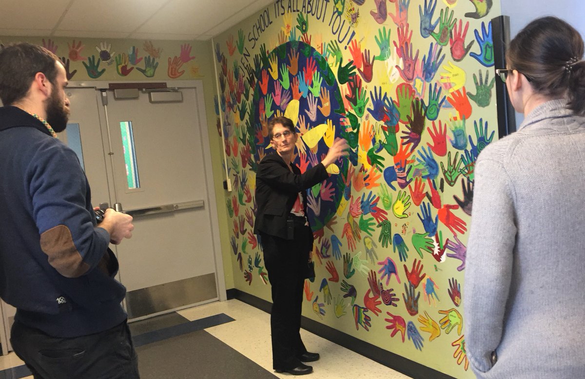 MaryvilleAcadem's tweet photo. We are very happy to welcome @FlashpointChi student James Cole to our #JenSchool campus today. Principal Ann Craig explains to James the Wall of Hands (and paws!) while Assistant Principal Heather Lischett listens. We'll share our exciting collab w/ #FlashpointChicago soon! https://t.co/G4juOKzJXq