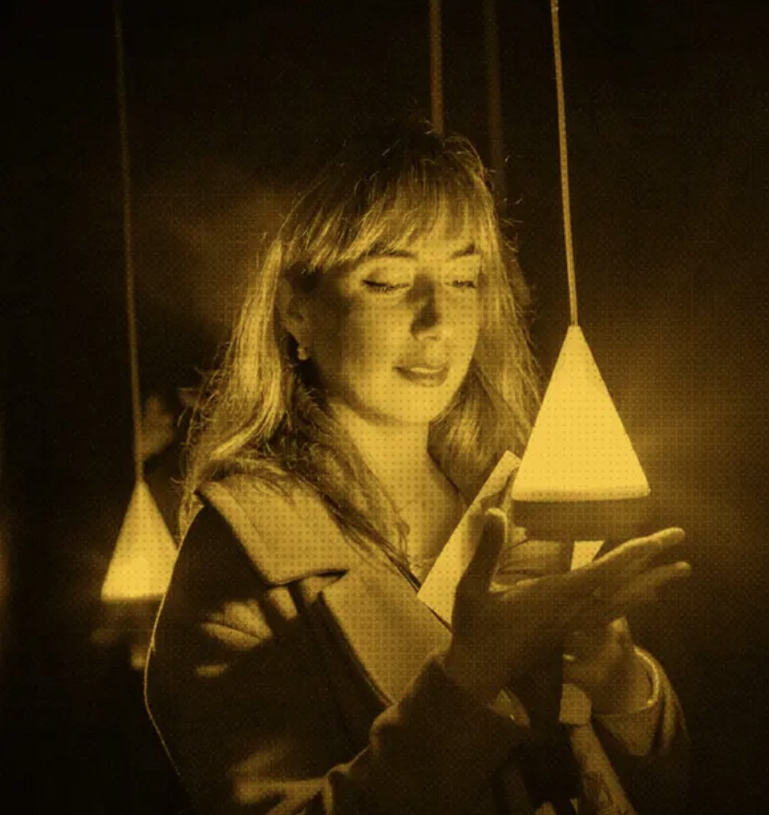 A young woman stares into a triangular light which she holds in her hand.