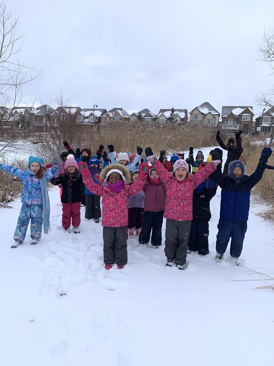 Image of a group of students in the snow with arms raised. 