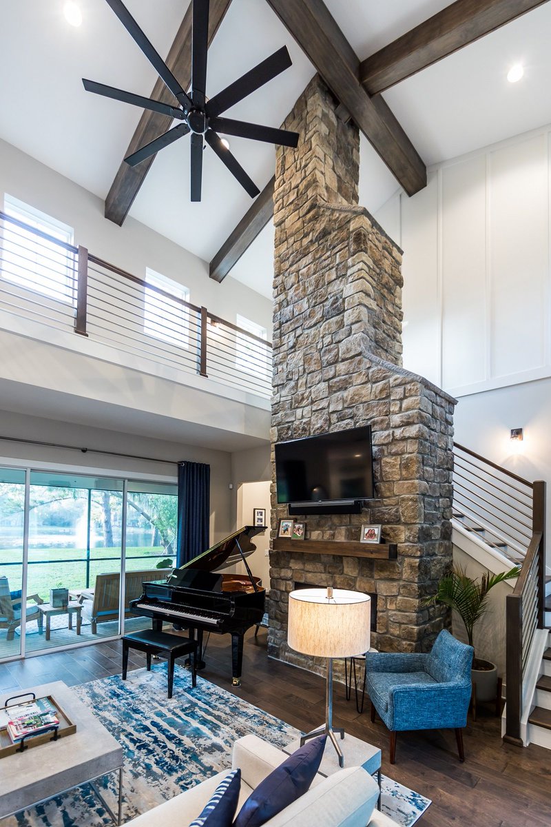 Our final featured great room this week is DreamDesign® 25: Springmoor House. The stone fireplace stretches to the vaulted ceiling with the staircase and balcony wrapping around it. Stunning! #dreambuilder #customhomesjacksonville #moderndesign #rusticfarmhouse #stonefireplace