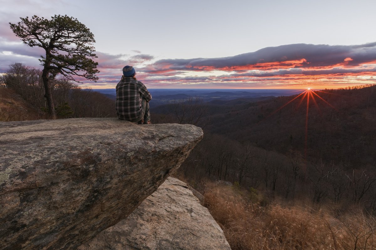 Man sits on an overlook watching a sunrise at Shenandoah.