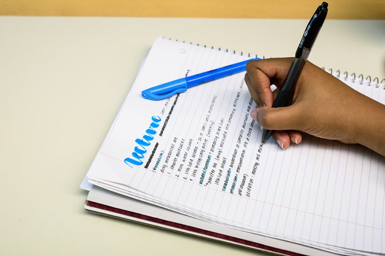 A hand using a pen to write in a notebook