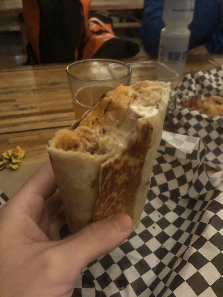 Me holding a quesarito partially eaten to show the gooey cheesy deliciousness inside