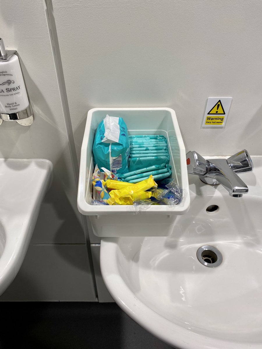 A basket sitting on a bathroom sink containing a mixture of sanitary products.