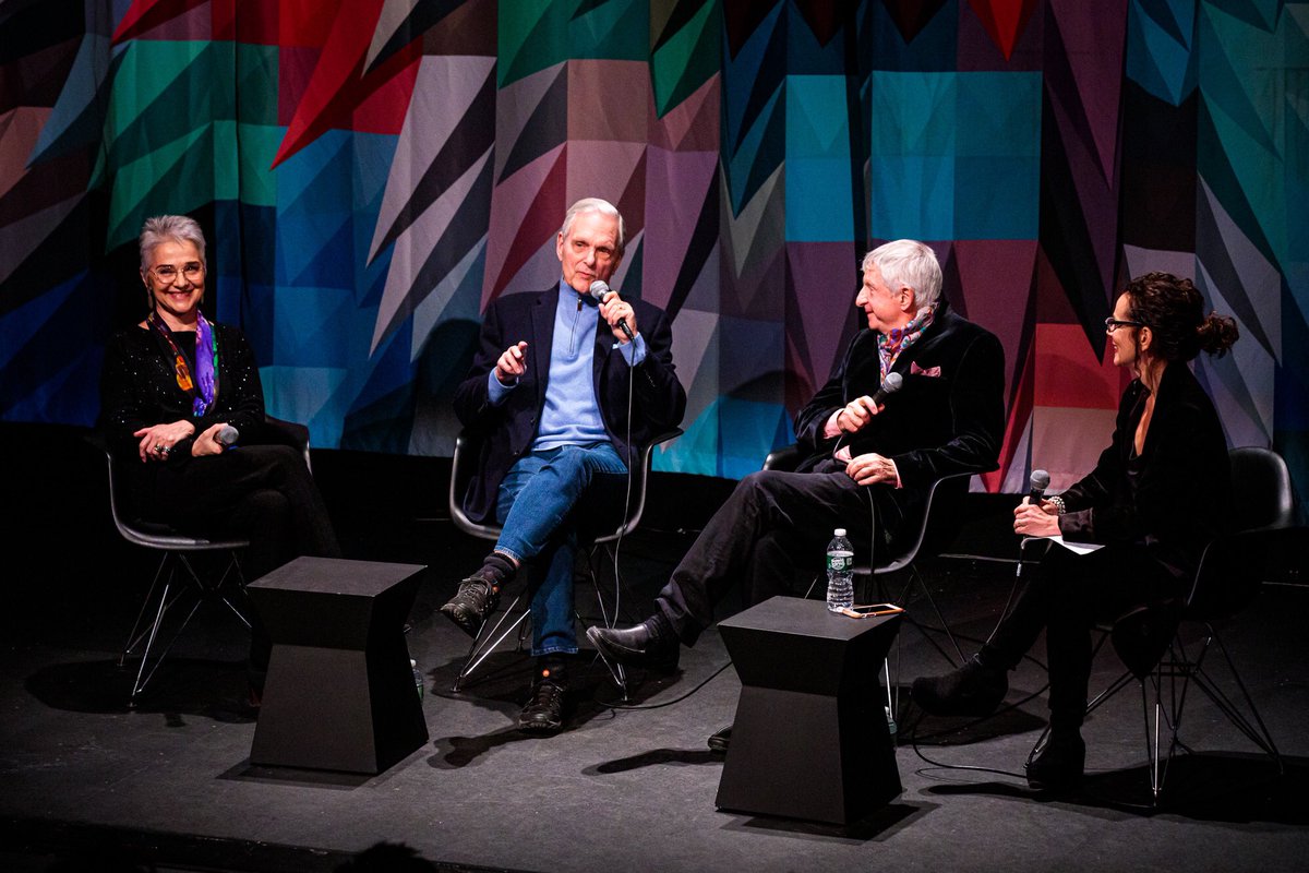 Four people seated on a stage with microphones