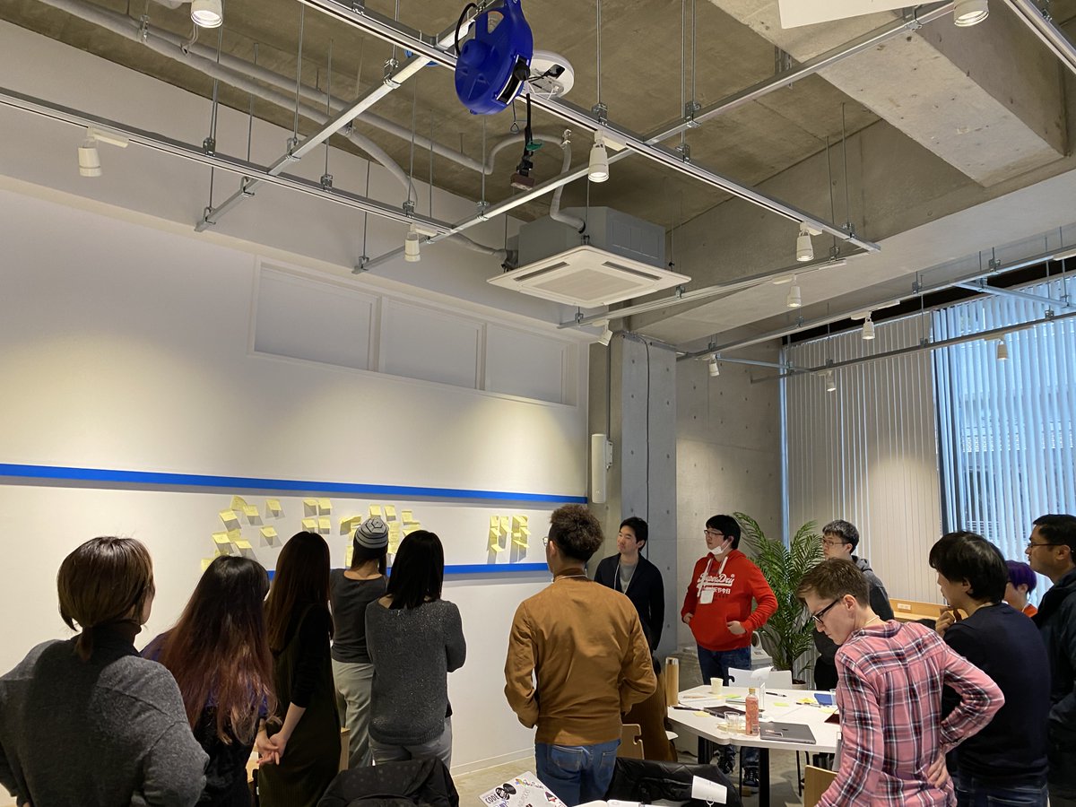 Standing attendees looking at and discussing a wall full of post-its.