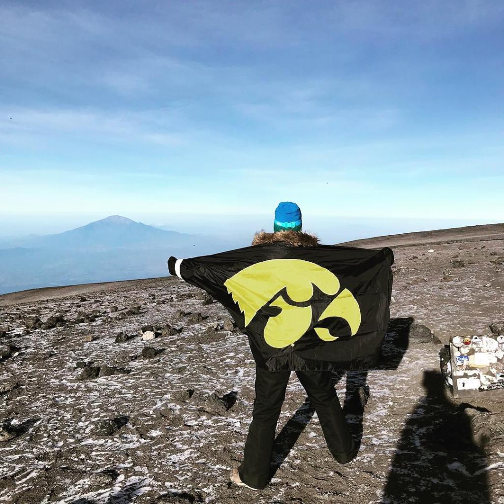 A person looks out at the mountain in the background while holding a Tigerhawk flag.