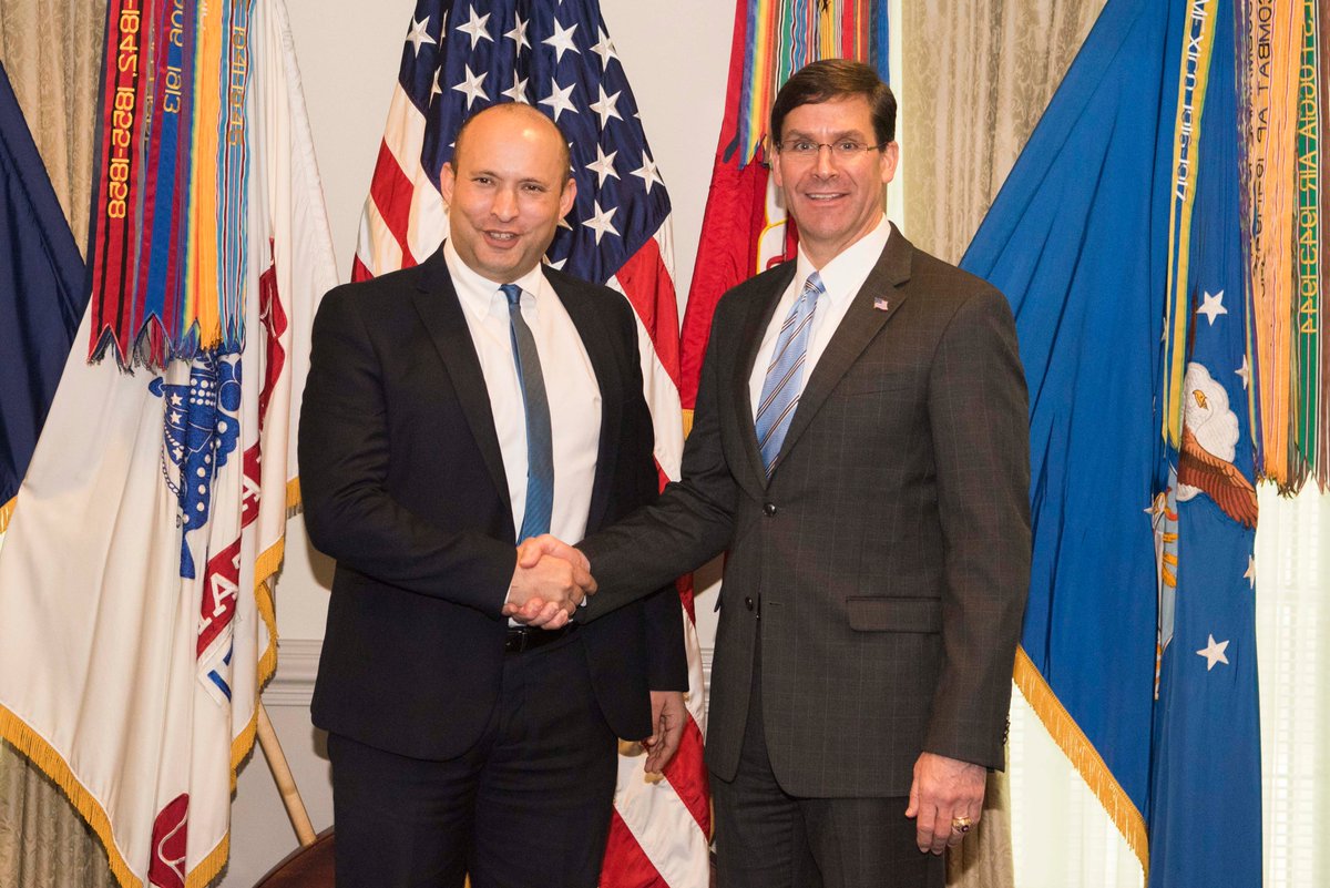 Esper and Bennett shake hands inside the Pentagon, in front of flags.
