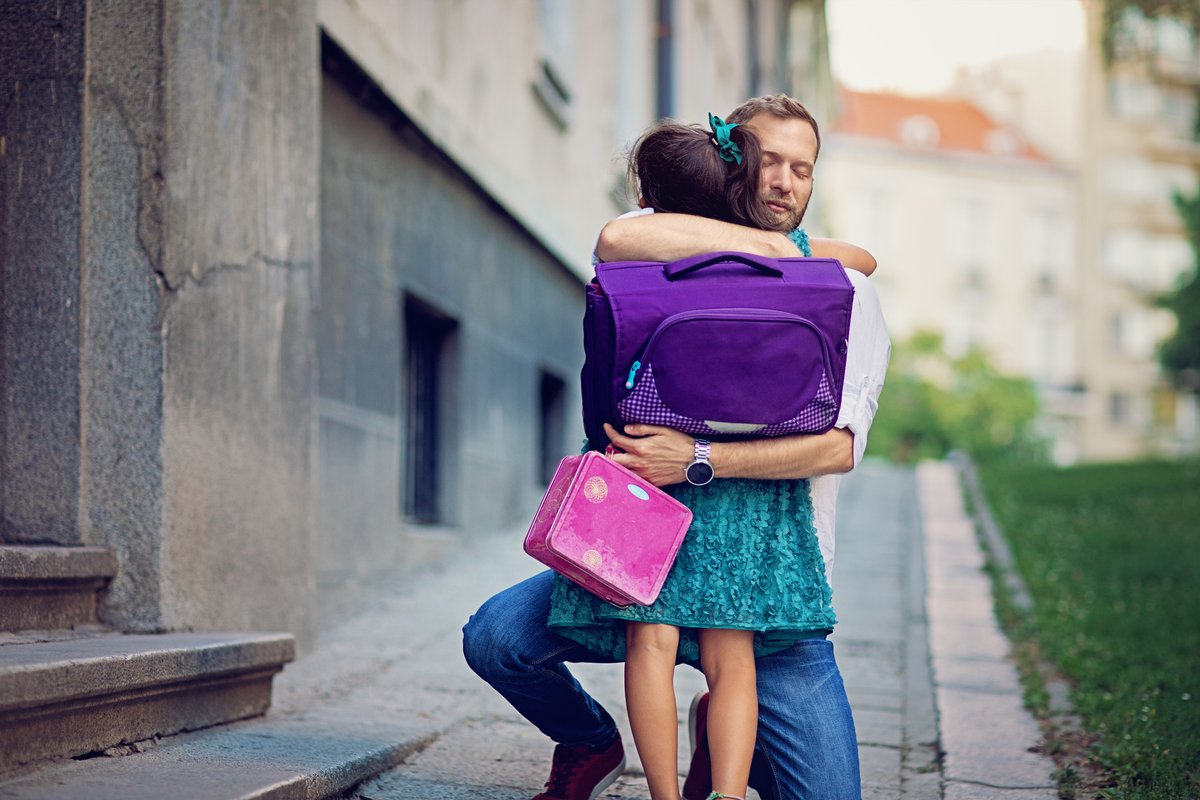 Image shows a young girl hugging her Dad.