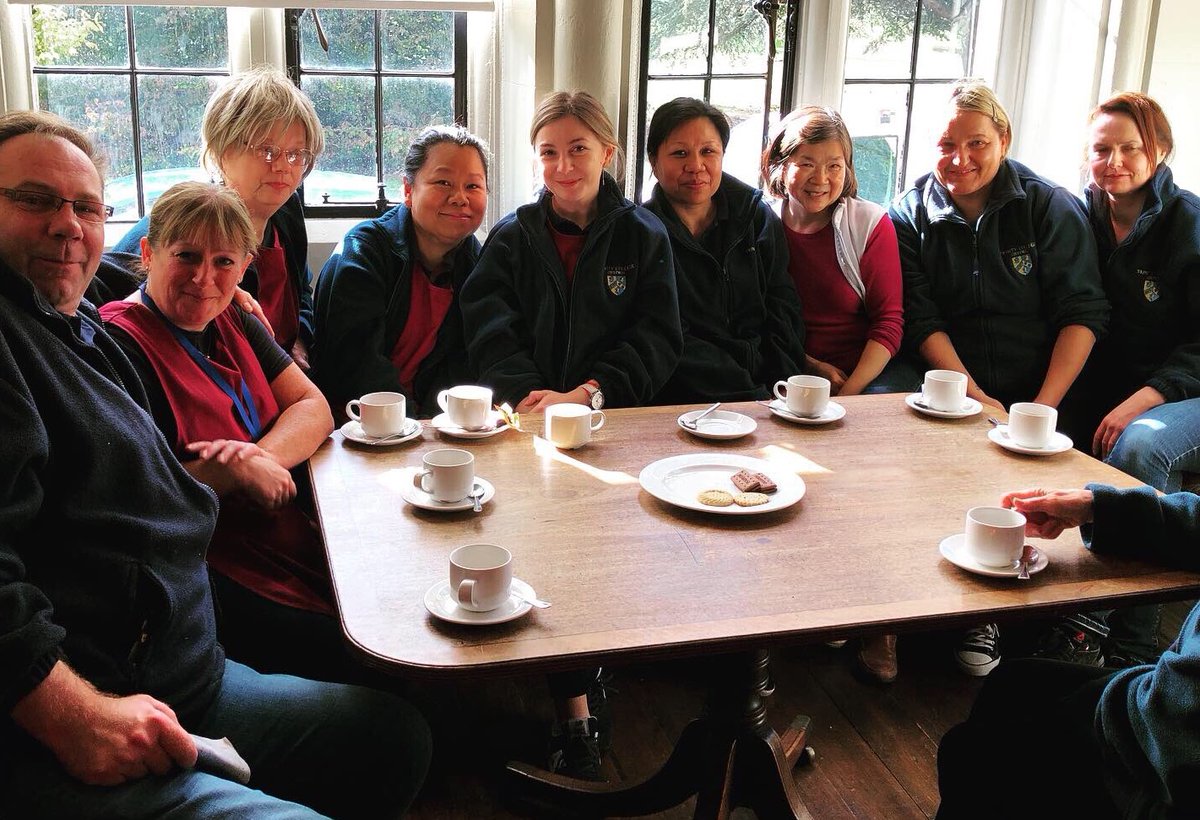 Trinity college staff sit around a coffee table.