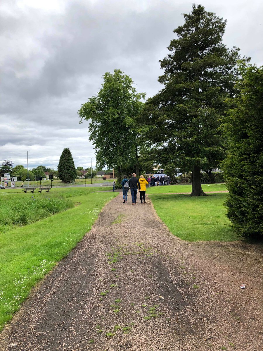a long shot of the walk, with people walking towards the trees at Woodhead Park, Kirkintilloch