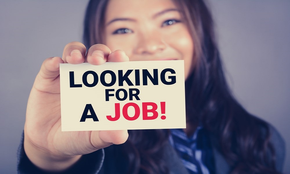 Young woman hold up a card which says "looking for a job"