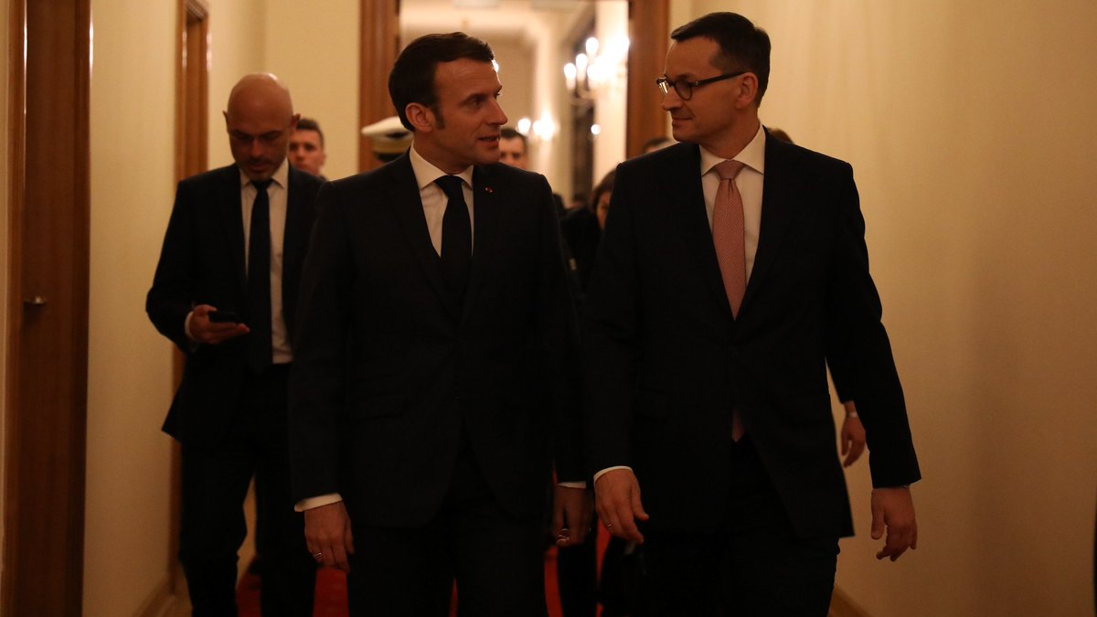 Prezydent Macron i premier Morawiecki idą korytarzem.