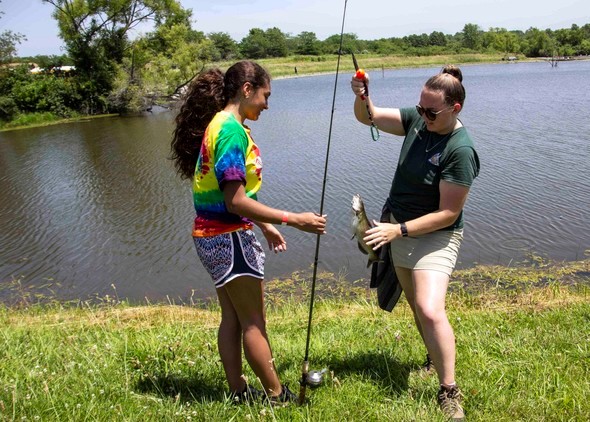 MDC staff help a teen get a fish off her line.