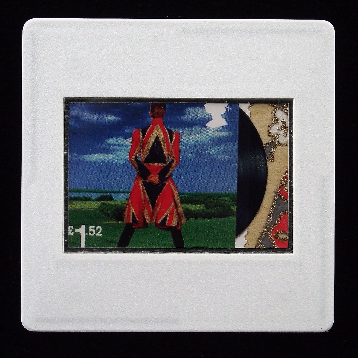 The image is of the album cover of Earthling printed on a Royal Mail postage stamp.  It has a breakout detail of a sliver of vinyl along the right hand perforated edge which is enhanced with a red, cream and gold Yuzen paper.  The stamp is encased in a white framed slide mount.