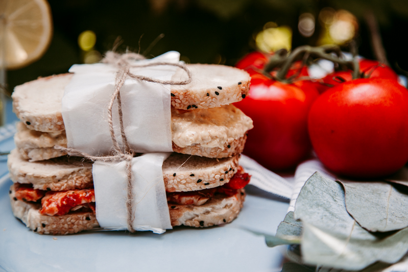 Sandwiches wrapped in greaseproof paper and tied with string.  Tomatoes in background