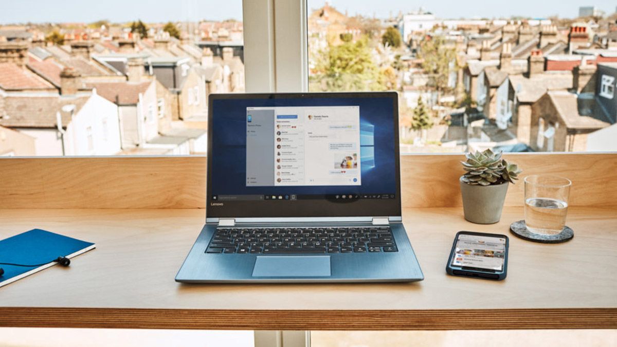 Closeup of a laptop with Windows 10 displayed. In the background is a surbuban landscape. 