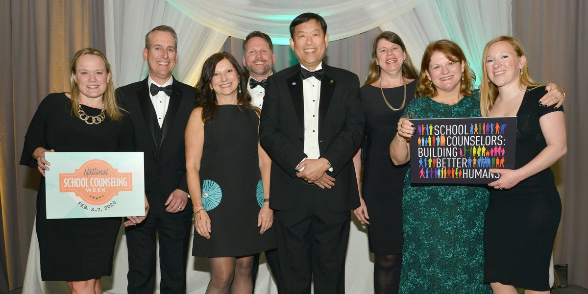 ASCA staff members with Happy National School Counseling Week sign and School Counselors: Building Better Humans sign