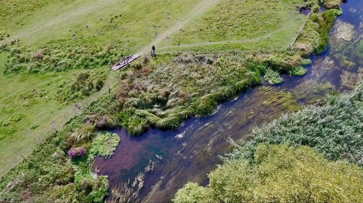 An aerial view of Stockbridge Marsh. A river runs through green fields.