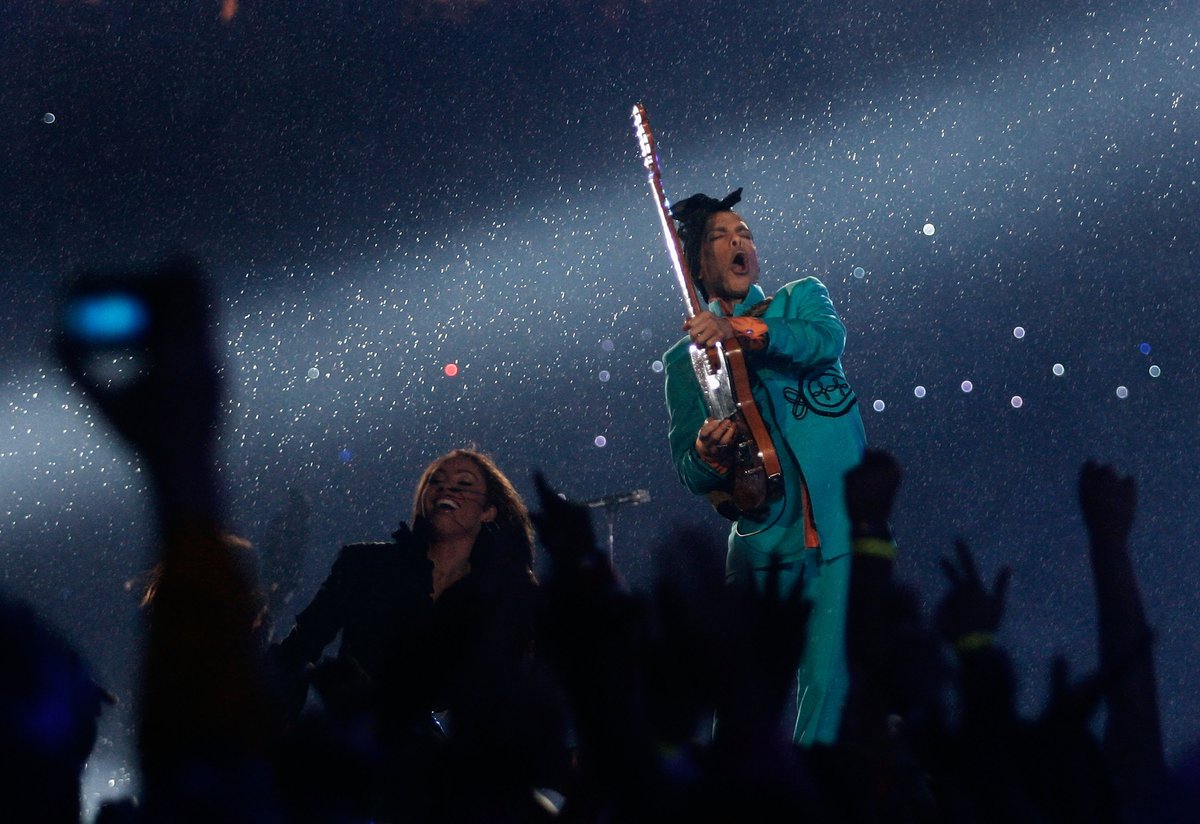 Prince, amazing guitarist plays in the rain, wearing a turquoise suit at Miami Dolphin Stadium in 2007.