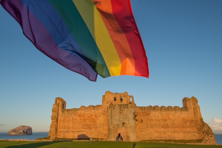 A rainbow flag in front of Tantallon Castle and the Bass Rock