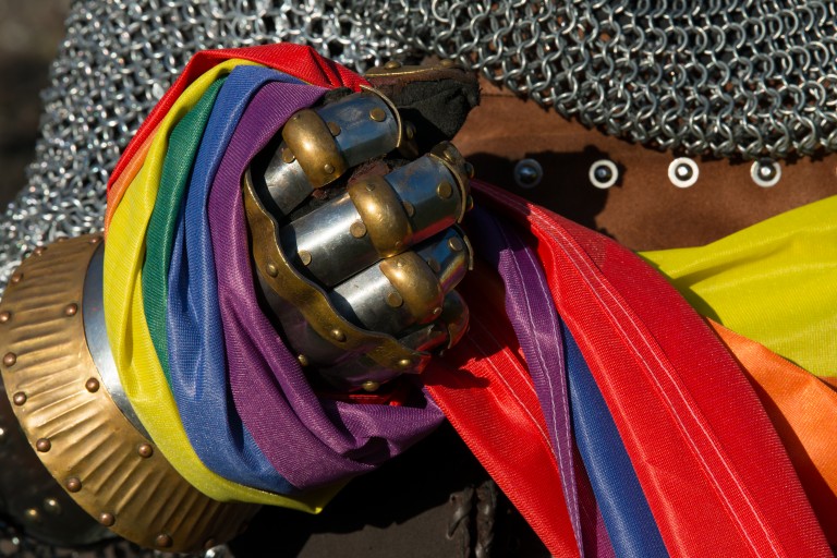 A rainbow flag being clasped by an armoured hand 