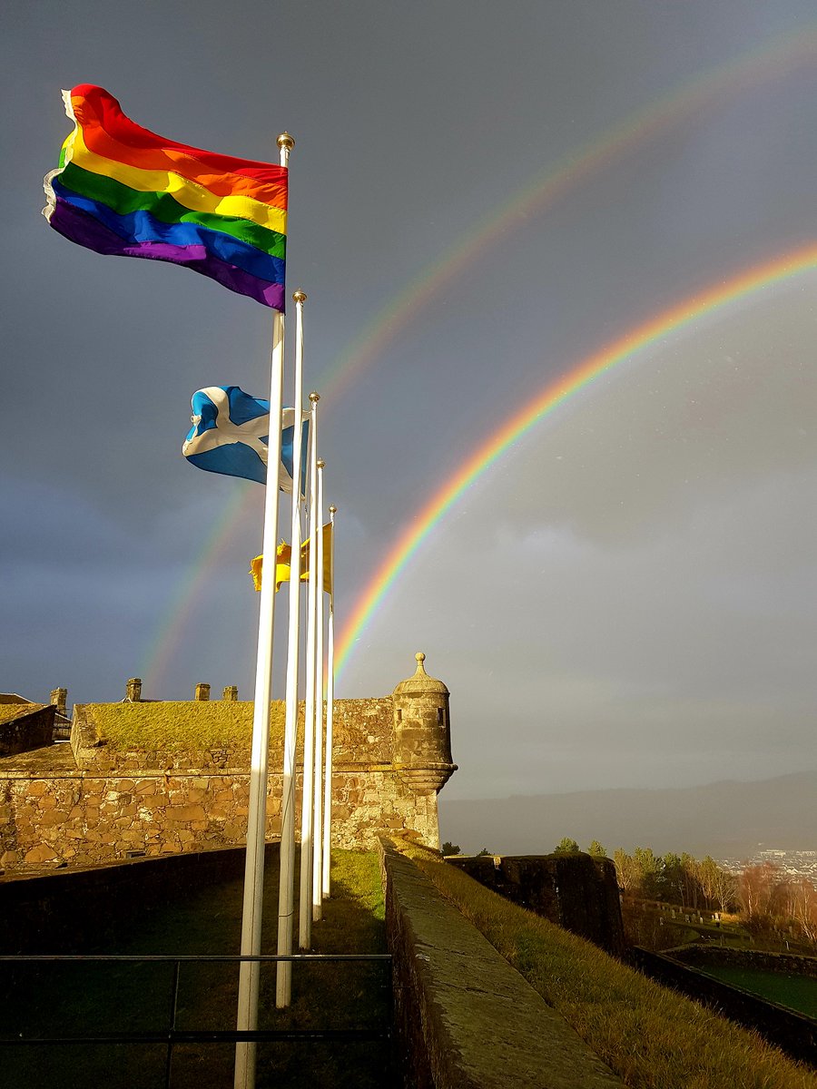 Flags including the Rainbow flag and the Saltire flying at Stirling Castle with a double rainbow in the background
