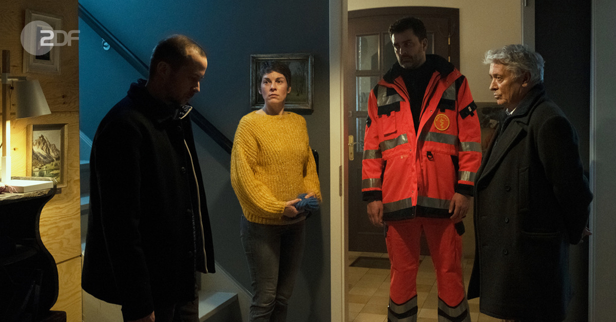 "Tage des letzten Schnees": Lars Eckert (Barnaby Metschurat) seine Frau Kirsten (Victoria Mayer), Kommissar Fischer (Henry Hübchen) und der Notarzt (Tilman Meyn) stehen in bedrückter Stimmung im Eingangsbereich eines Hauses. Montag, 20:15 uhr im ZDF.