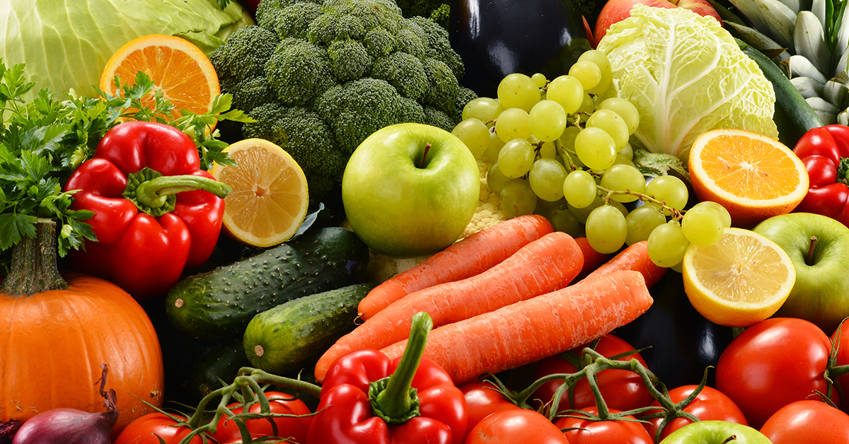 A photo of fresh fruits and vegetables such as apples, oranges, peppers, cucumbers, carrots and tomatoes.