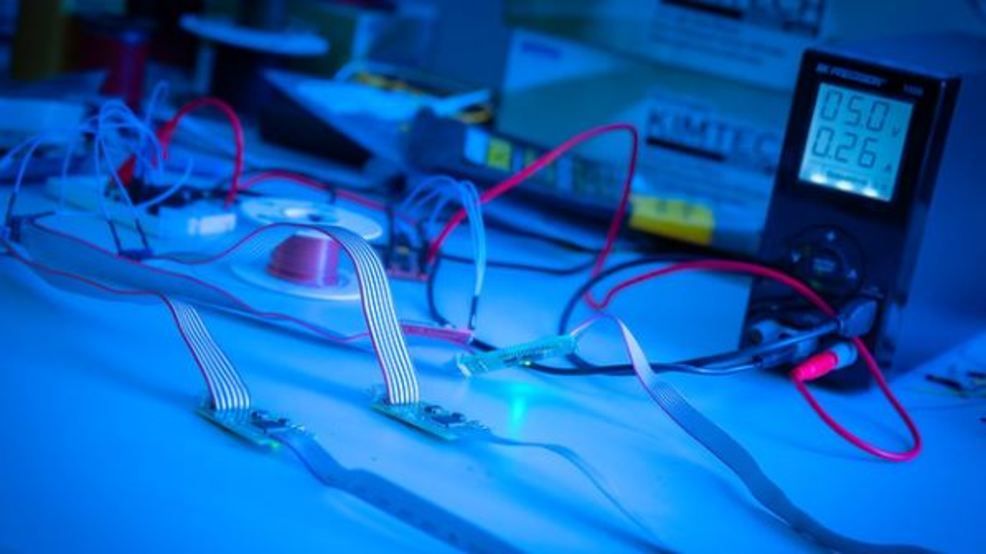 A blue tinted photos of wires and a digital meter. 