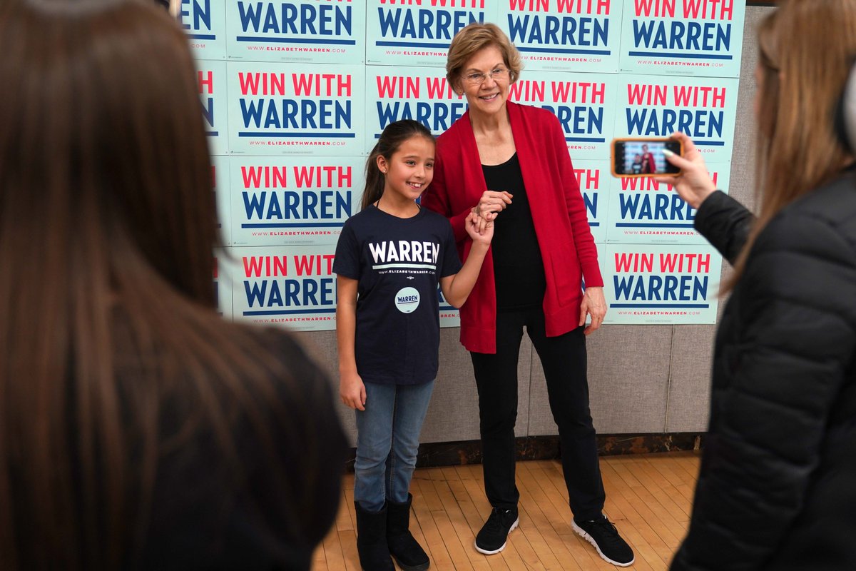 Elizabeth Warren makes a pinkie promise with a young girl.