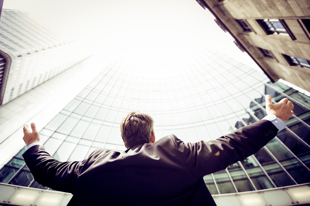 low-angle photography of man in middle of buildings looking up