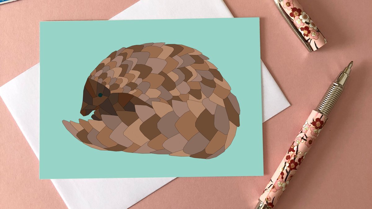An illustrated greeting card of a pangolin surrounded by stamps, washi tape and a pen