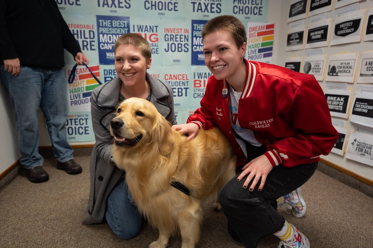 Two supporters pose for a selfie with Elizabeth's dog, Bailey.