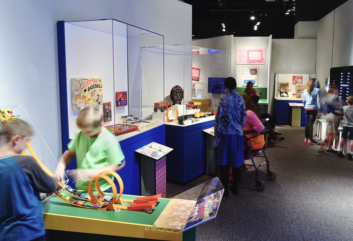 Children playing on Hot Wheels racing tracks inside the exhibit, “Toy Boom! Toys from the 1950s & ‘60s!”