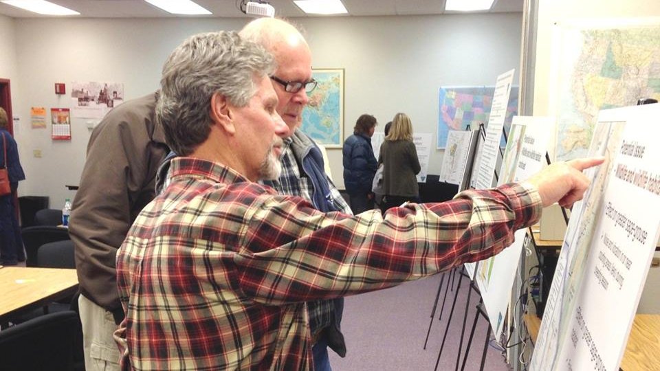 Photo of two men standing in front of a map at a BLM public meeting.